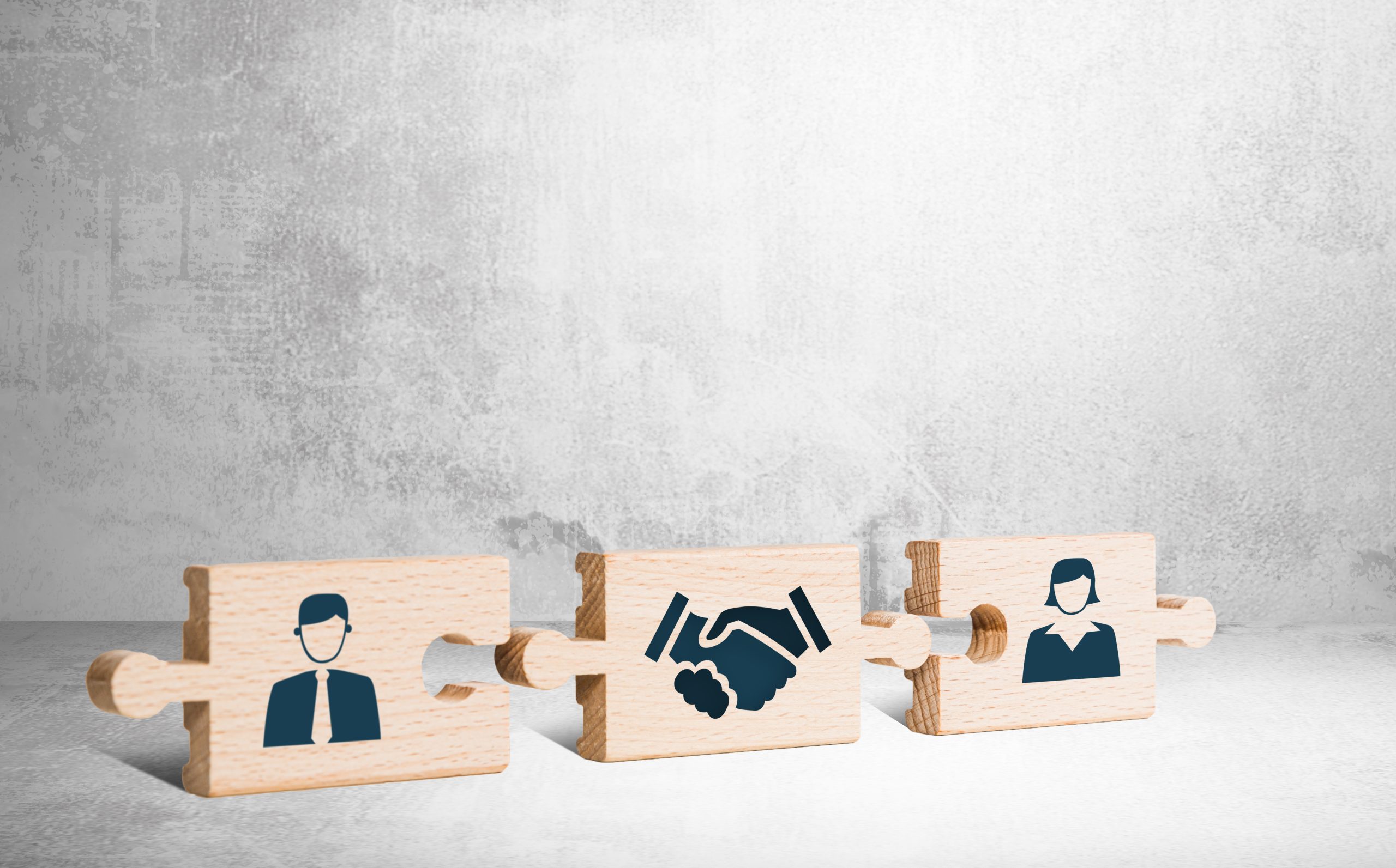 three puzzle pieces on gray background: man, woman, and shaking hands. Represents complexities of guardianship for severe mental illness, with alternatives like supported decision-making