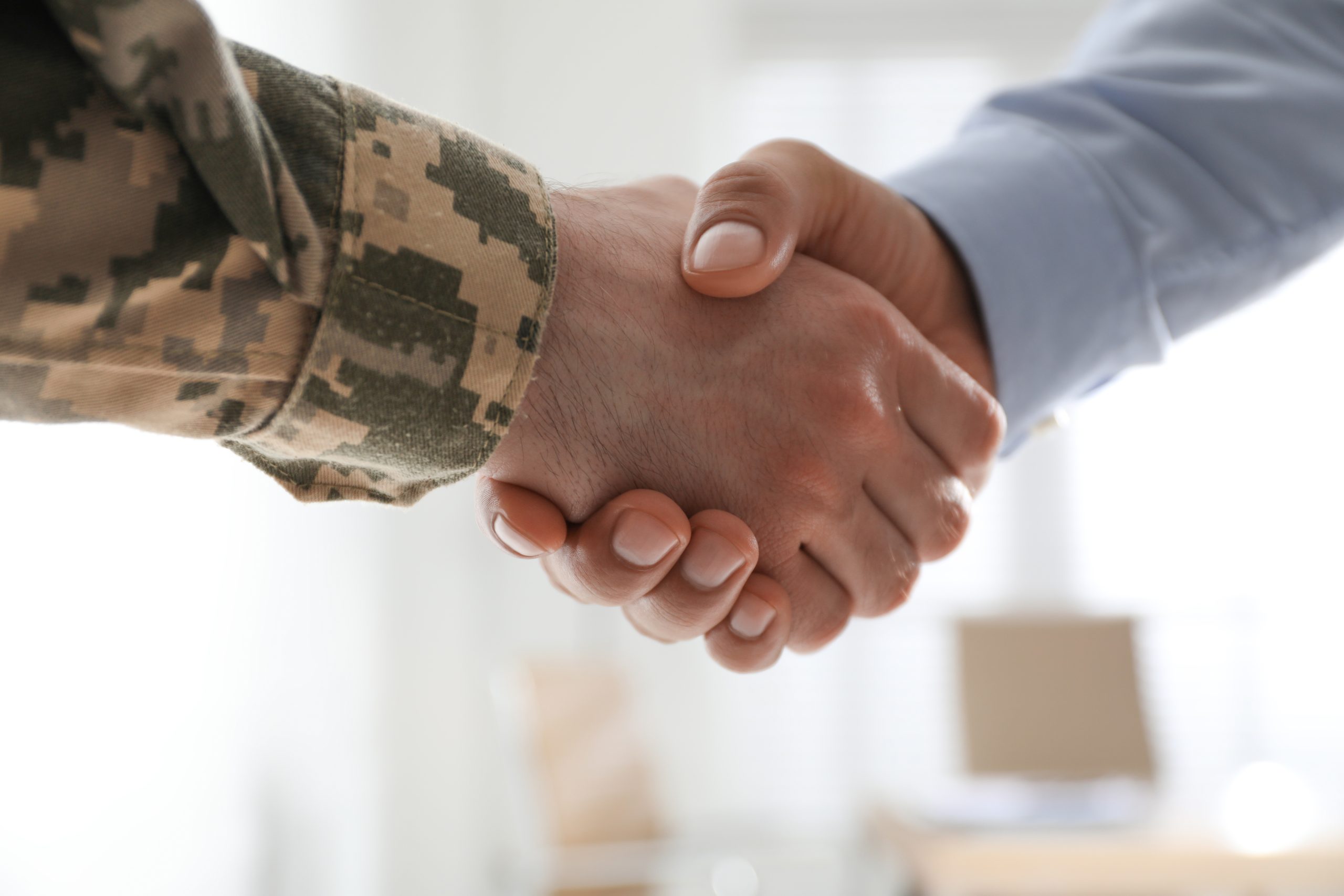 photo of a handshake between two hands, one in camouflage, representing veterans accessing mental health support services