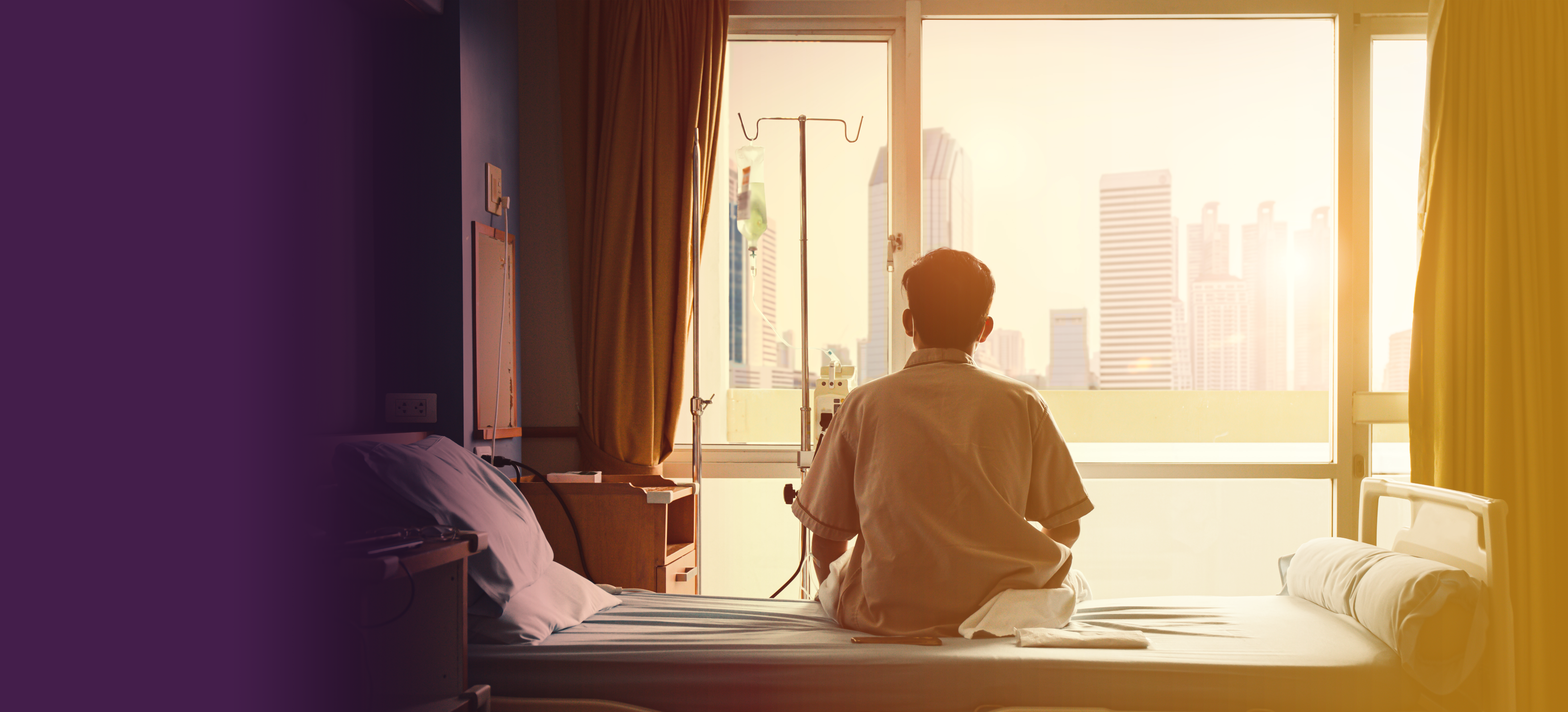 Individual seated on a psychiatric hospital bed, looking out the window. Symbolic image representing the pressing issue of psychiatric inpatient bed shortages in America